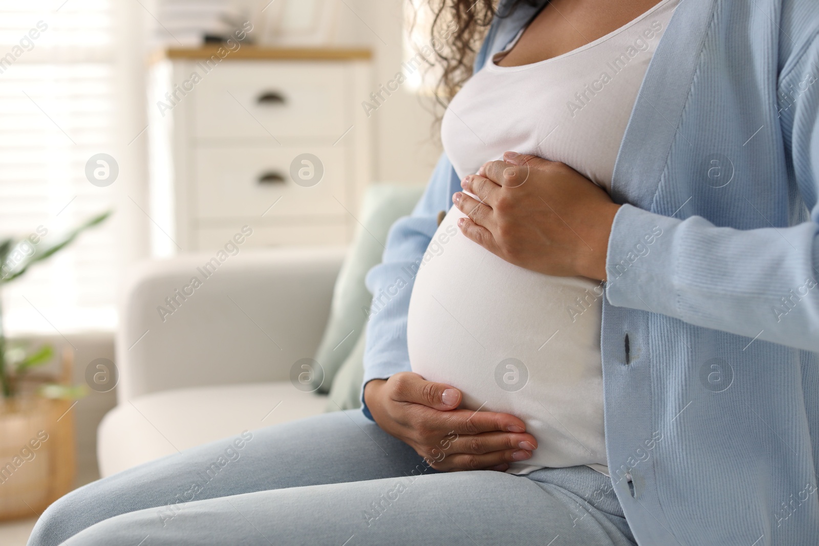 Photo of Pregnant woman on sofa at home, closeup