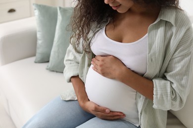 Photo of Pregnant woman on sofa at home, closeup