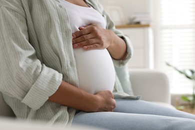 Photo of Pregnant woman on sofa at home, closeup