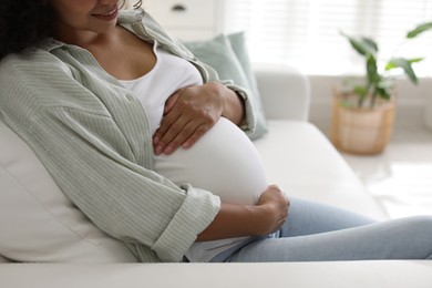 Pregnant woman on sofa at home, closeup