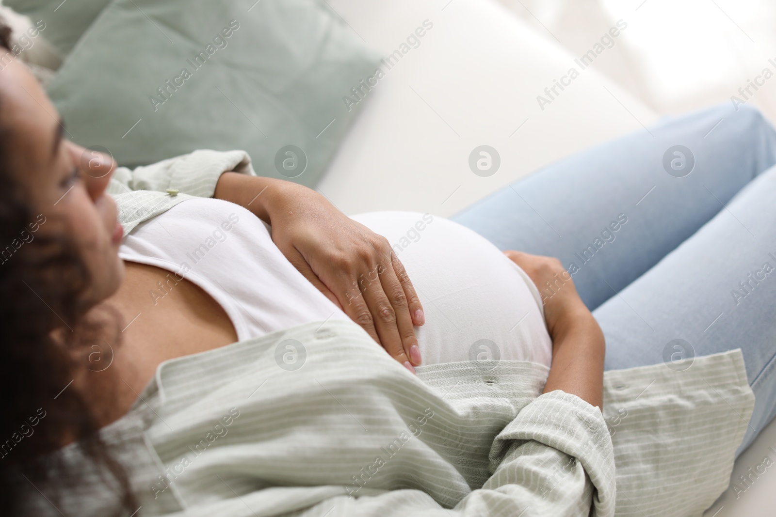 Photo of Pregnant woman on sofa at home, closeup