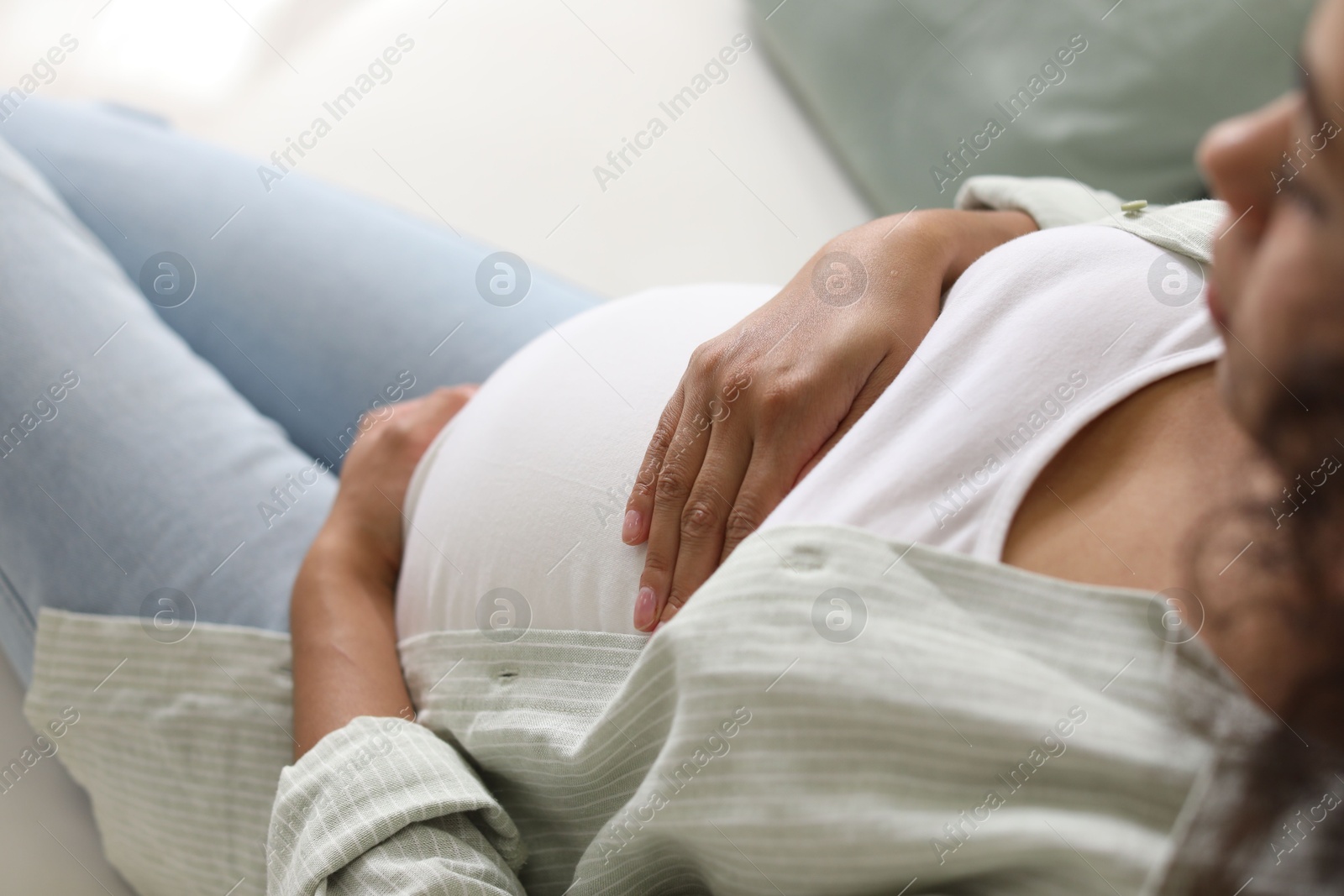 Photo of Pregnant woman on sofa at home, closeup