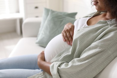 Photo of Pregnant woman on sofa at home, closeup