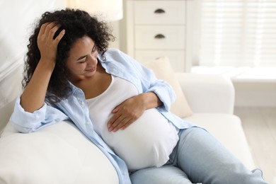 Portrait of beautiful pregnant woman on sofa at home