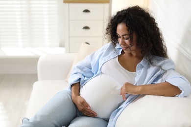 Photo of Portrait of beautiful pregnant woman on sofa at home