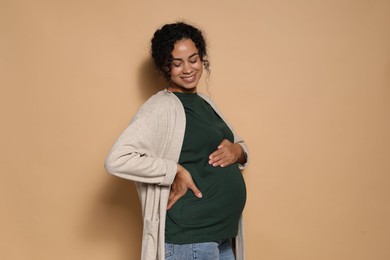 Portrait of beautiful pregnant woman on beige background