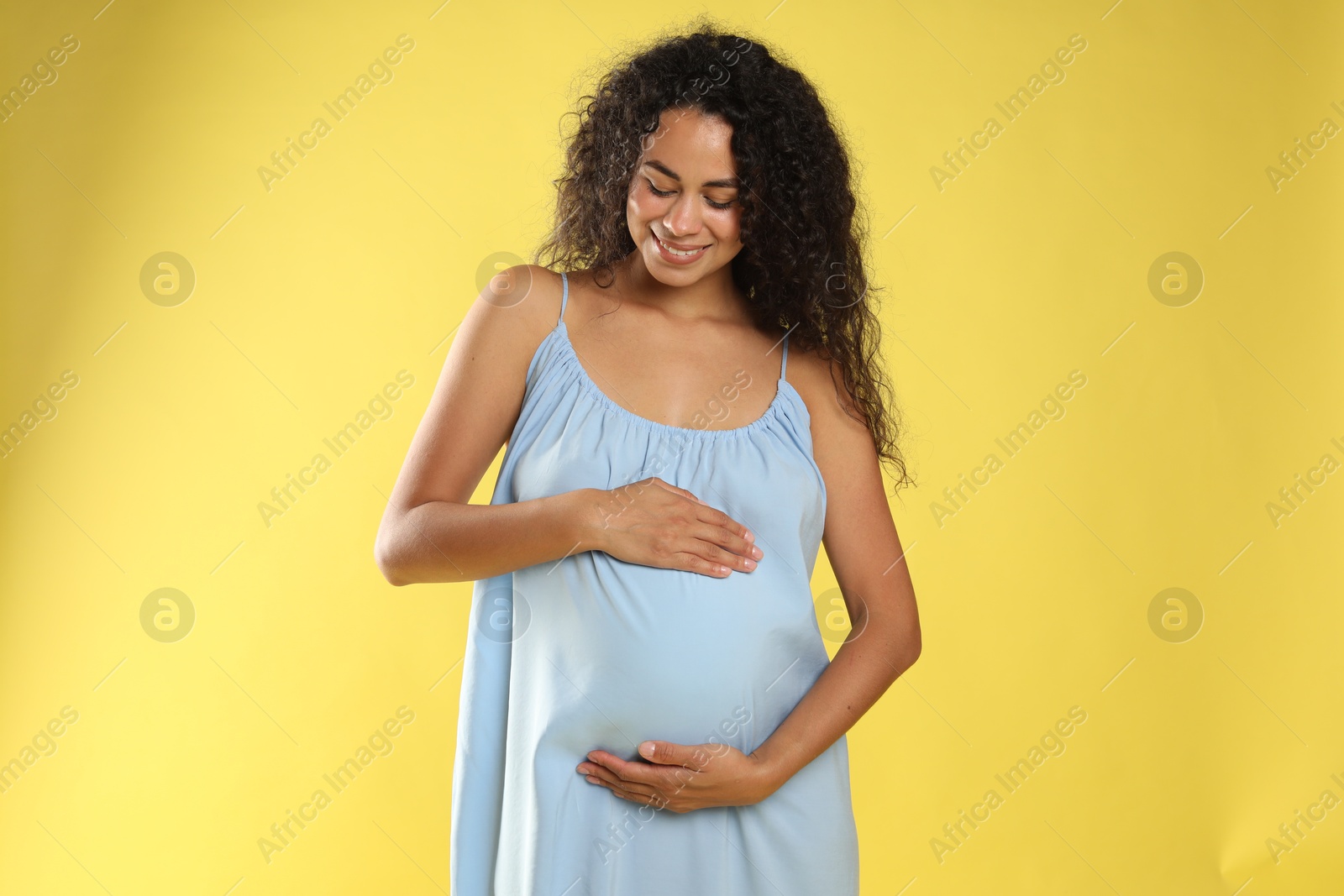 Photo of Portrait of beautiful pregnant woman on yellow background