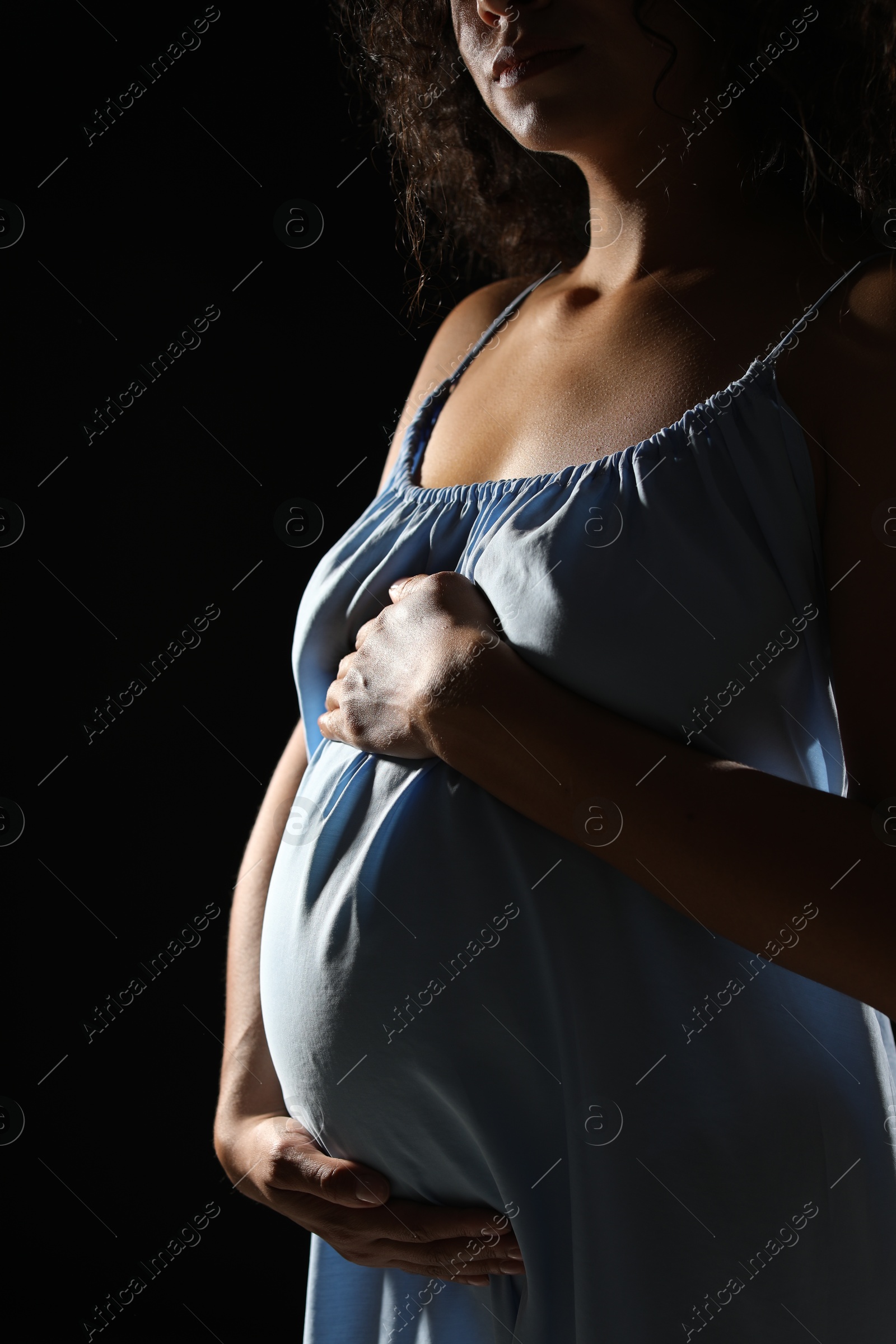 Photo of Pregnant woman on black background, closeup view