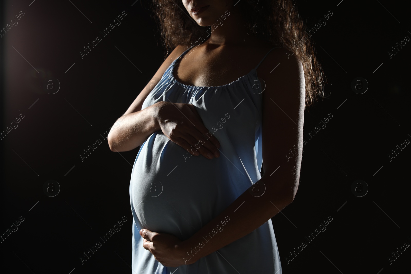 Photo of Pregnant woman on black background, closeup view