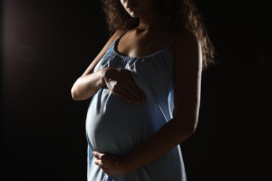 Photo of Pregnant woman on black background, closeup view