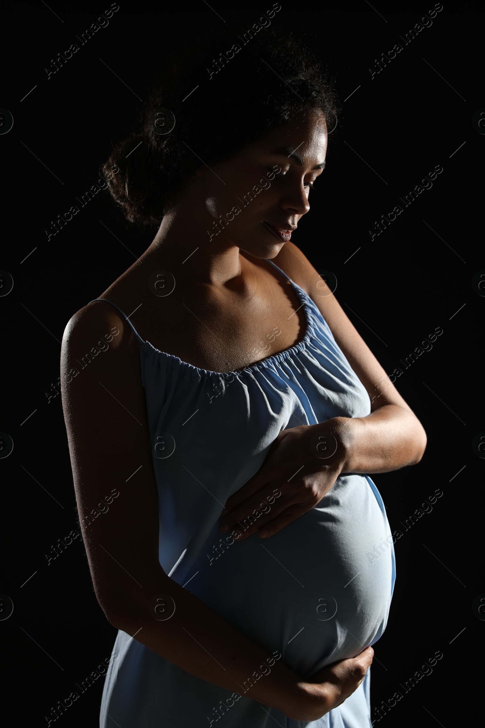 Photo of Portrait of beautiful pregnant woman on black background