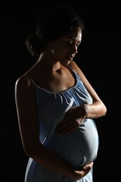 Portrait of beautiful pregnant woman on black background