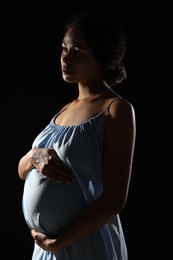 Photo of Portrait of beautiful pregnant woman on black background