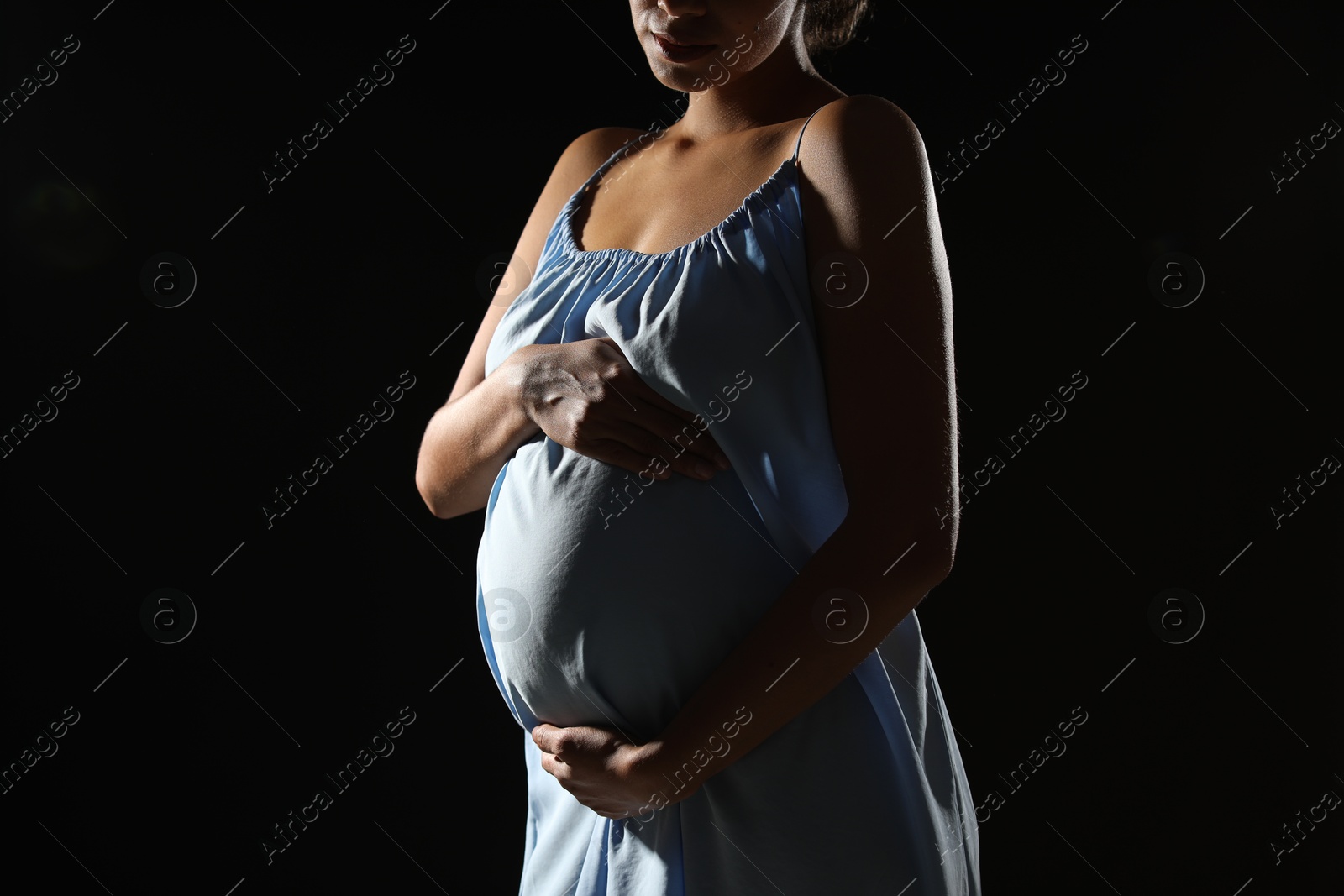 Photo of Pregnant woman on black background, closeup view