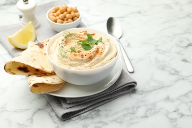 Photo of Delicious hummus with paprika, pita and chickpeas on white marble table