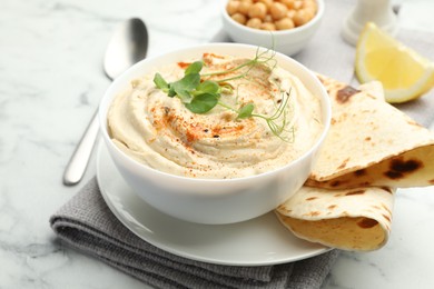 Photo of Delicious hummus with paprika, pita and chickpeas on white marble table, closeup