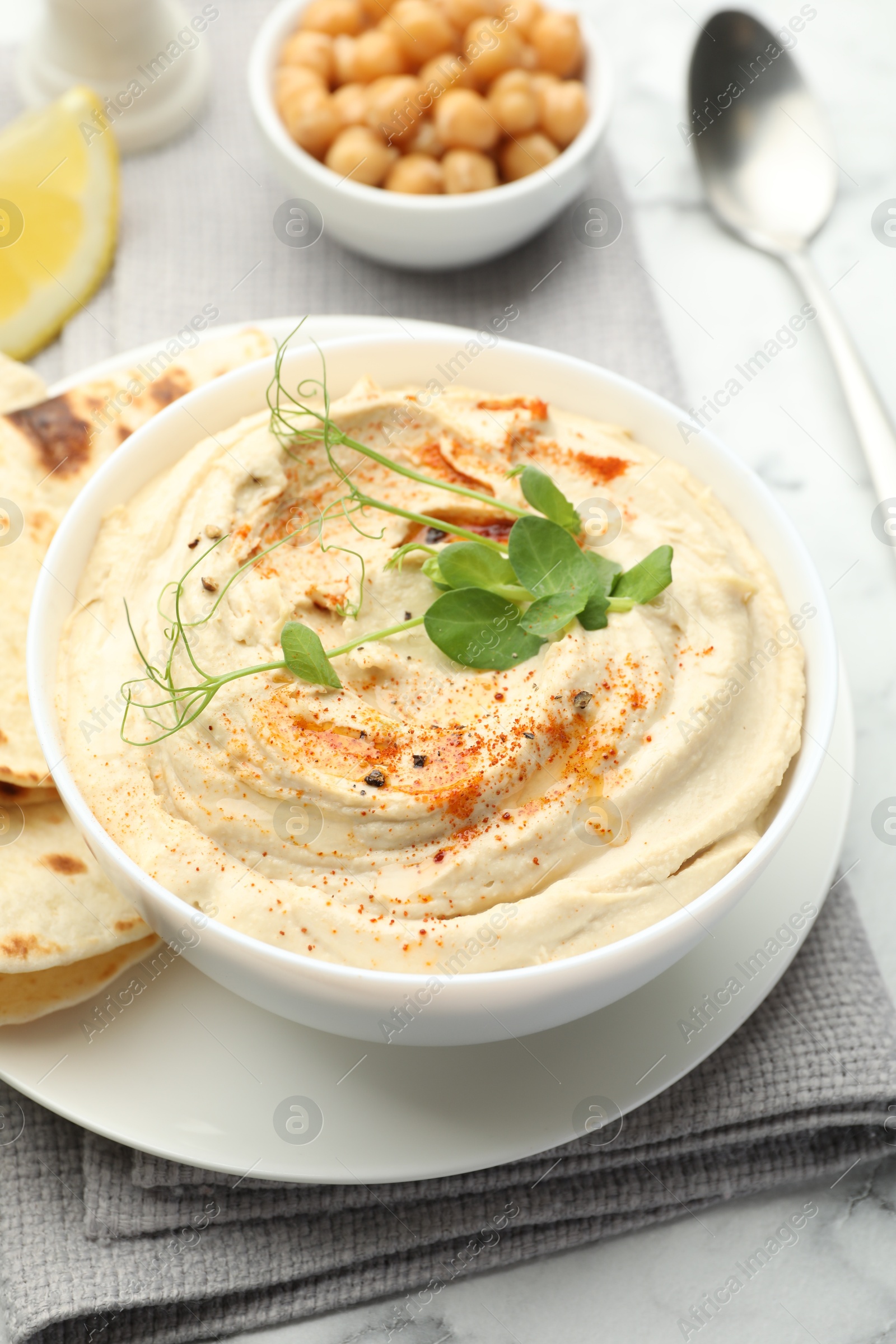 Photo of Delicious hummus with paprika, pita and chickpeas on table, closeup