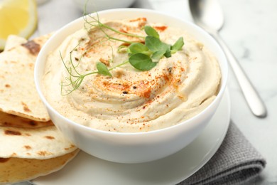 Photo of Delicious hummus with paprika in bowl and pita on table, closeup