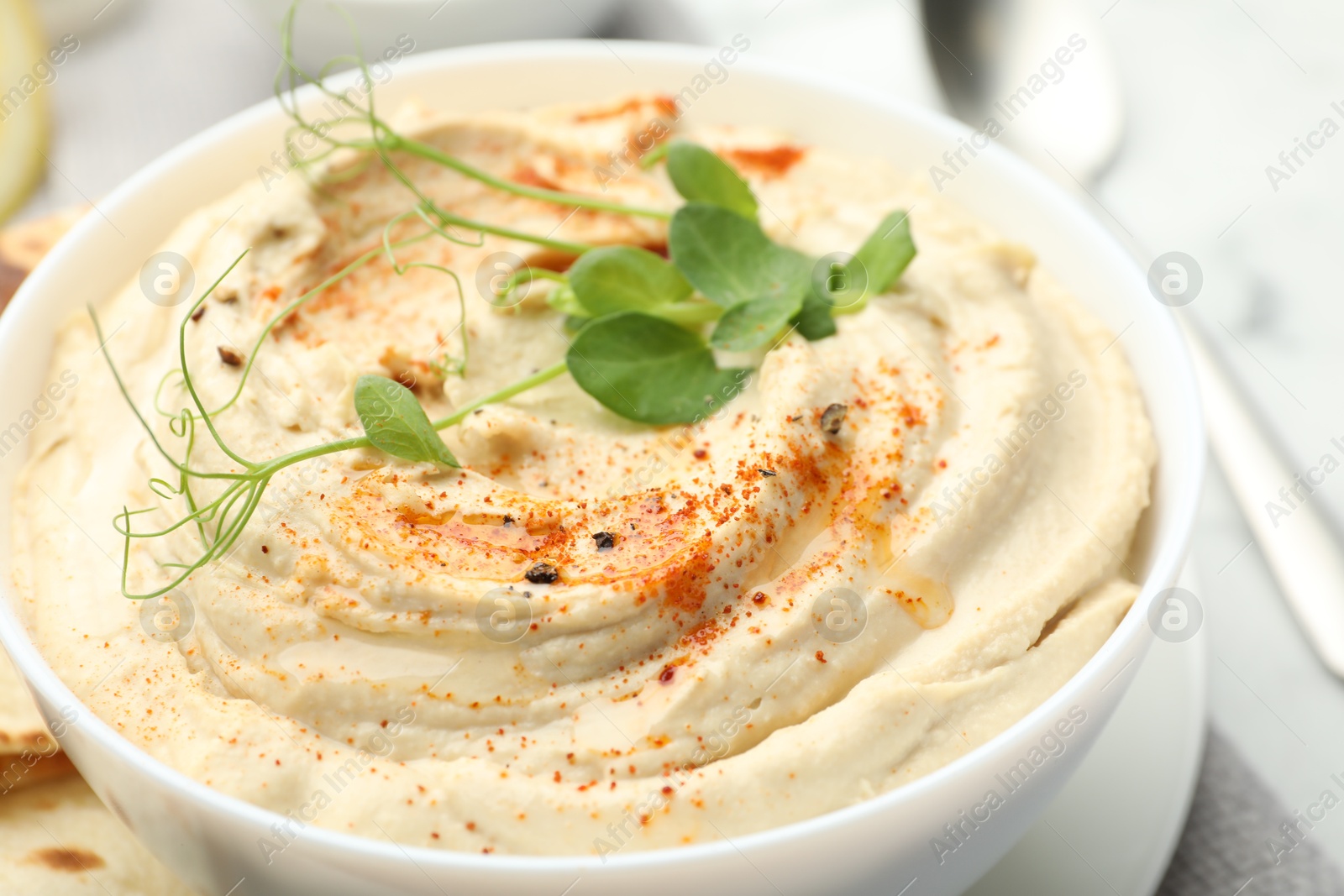 Photo of Delicious hummus with paprika in bowl on table, closeup