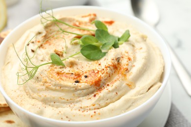 Delicious hummus with paprika in bowl on table, closeup