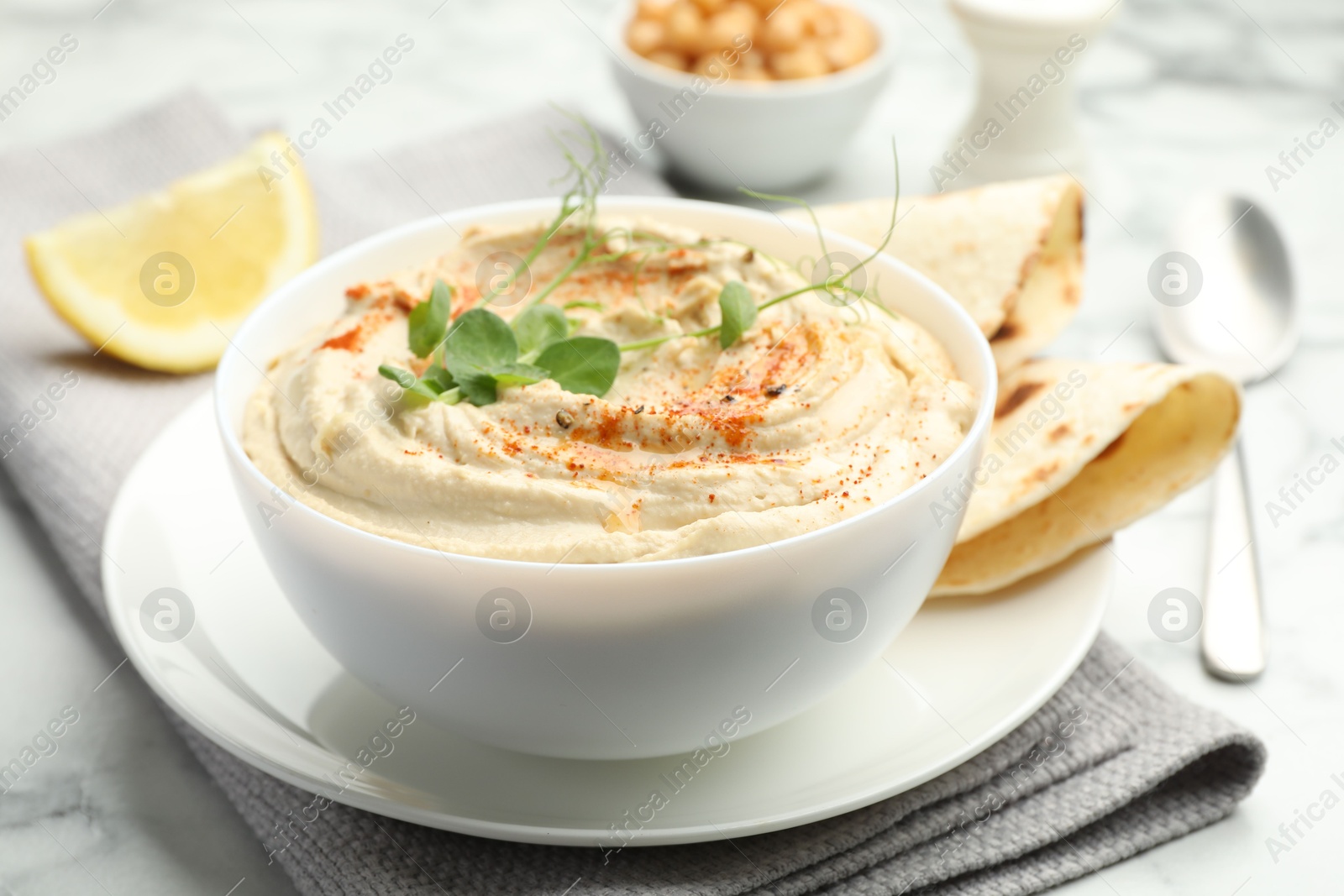 Photo of Delicious hummus with paprika and pita on white marble table, closeup