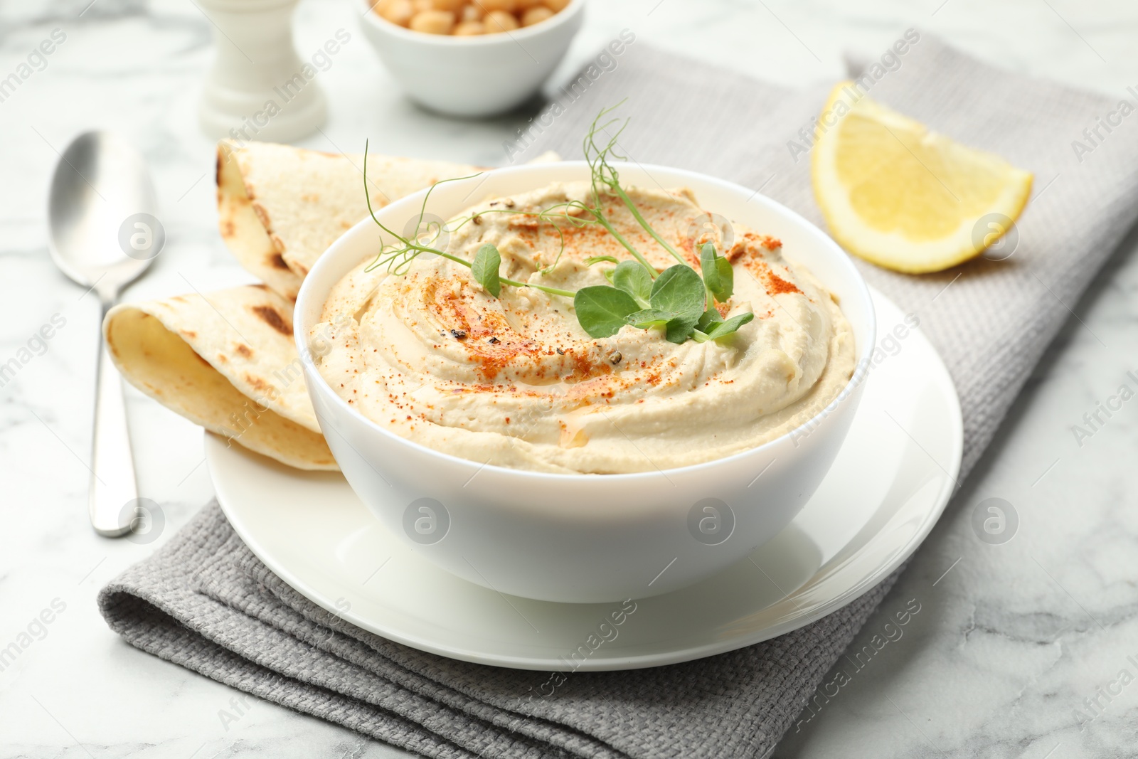 Photo of Delicious hummus with paprika and pita on white marble table, closeup