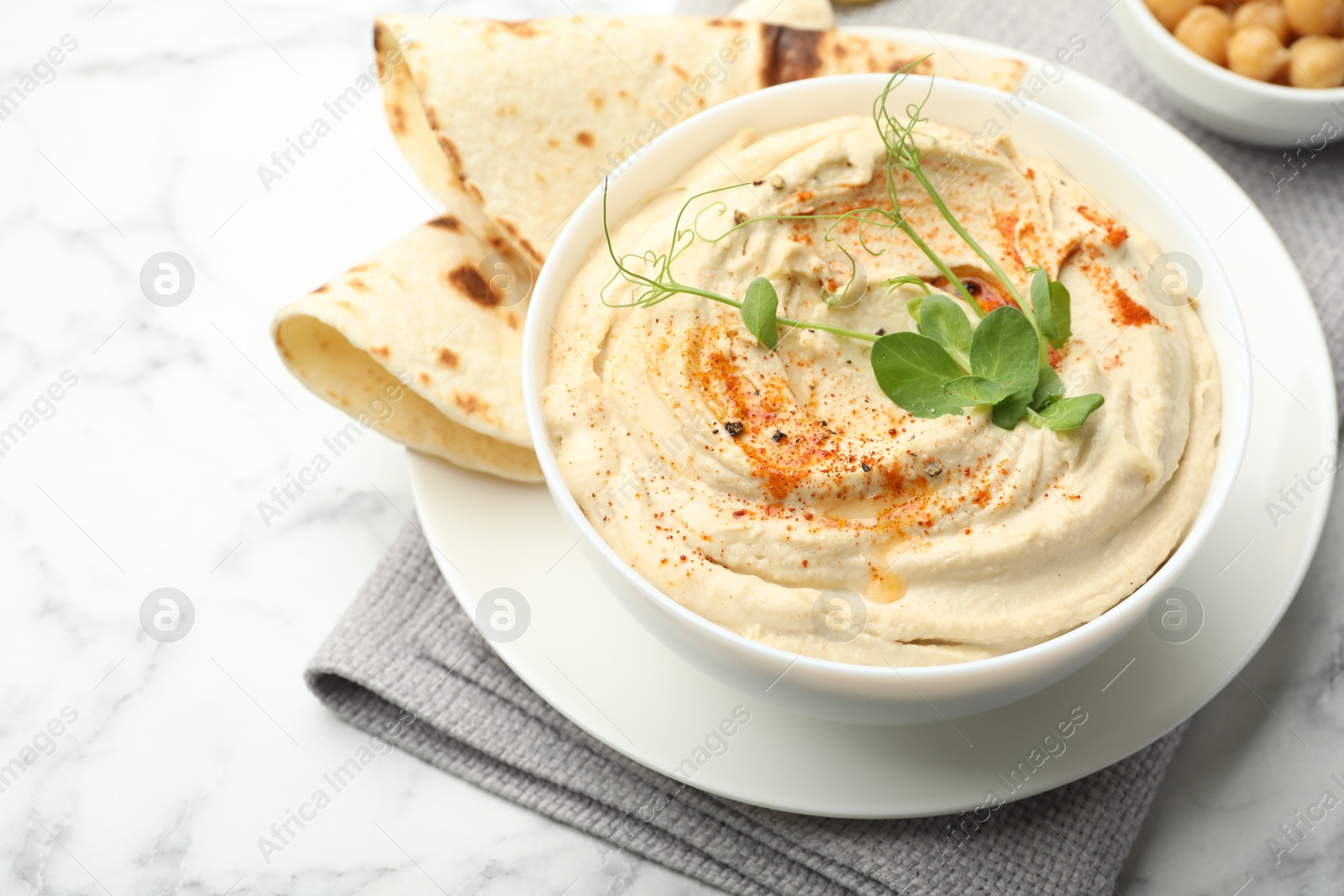 Photo of Delicious hummus with paprika and pita on white marble table, closeup