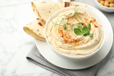 Delicious hummus with paprika and pita on white marble table, closeup