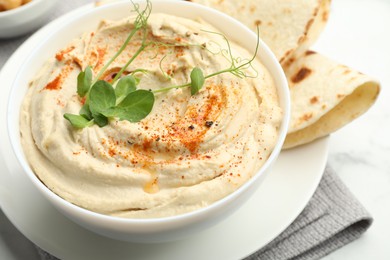 Photo of Delicious hummus with paprika in bowl and pita on table, closeup