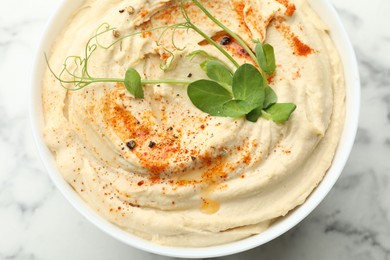 Photo of Delicious hummus with paprika in bowl on white marble table, top view