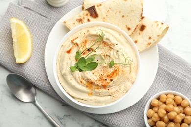 Photo of Delicious hummus with paprika, pita and chickpeas on white marble table, top view