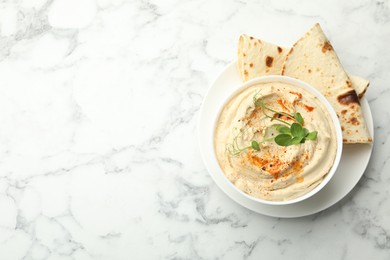 Photo of Delicious hummus with paprika and pita on white marble table, top view. Space for text