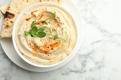 Photo of Delicious hummus with paprika and pita on white marble table, top view