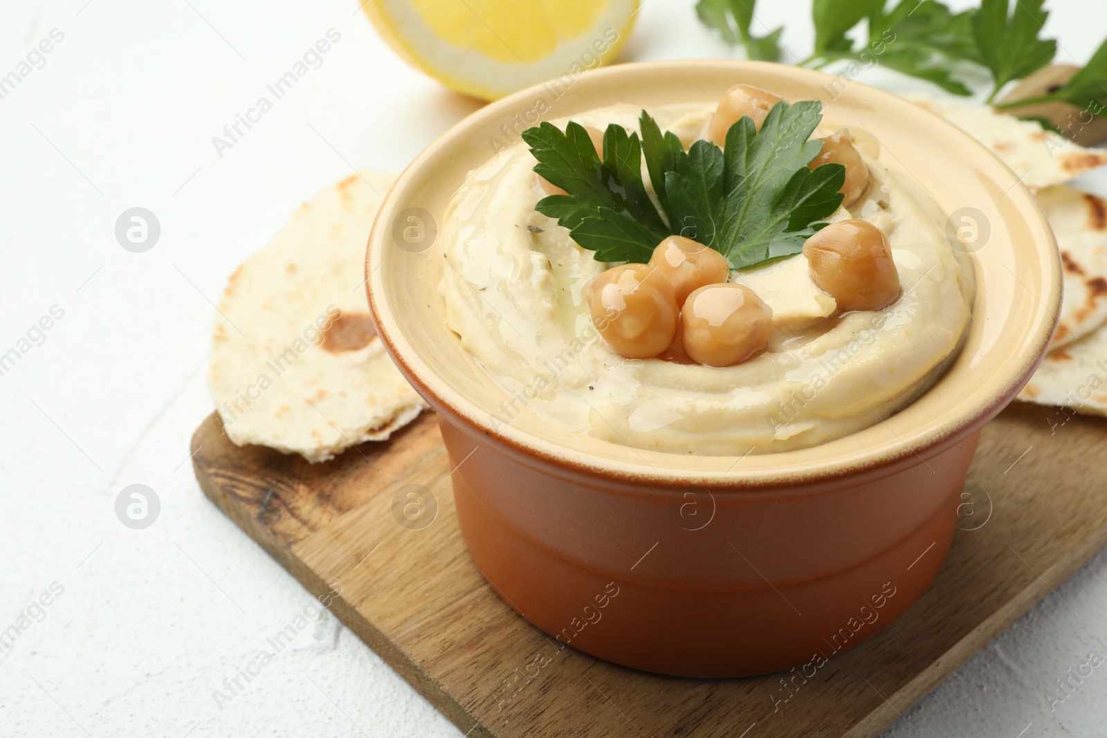 Photo of Delicious hummus with parsley, chickpeas and pita on white table, closeup