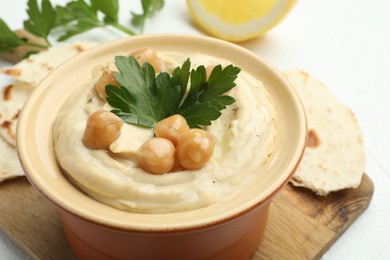 Photo of Delicious hummus with parsley, chickpeas and pita on white table, closeup