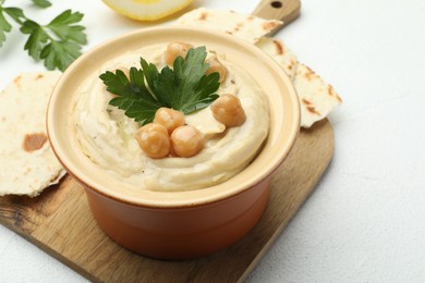 Photo of Delicious hummus with parsley, chickpeas and pita on white table, closeup