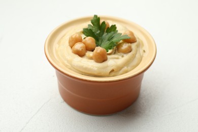 Photo of Delicious hummus with parsley and chickpeas in bowl on white table, closeup