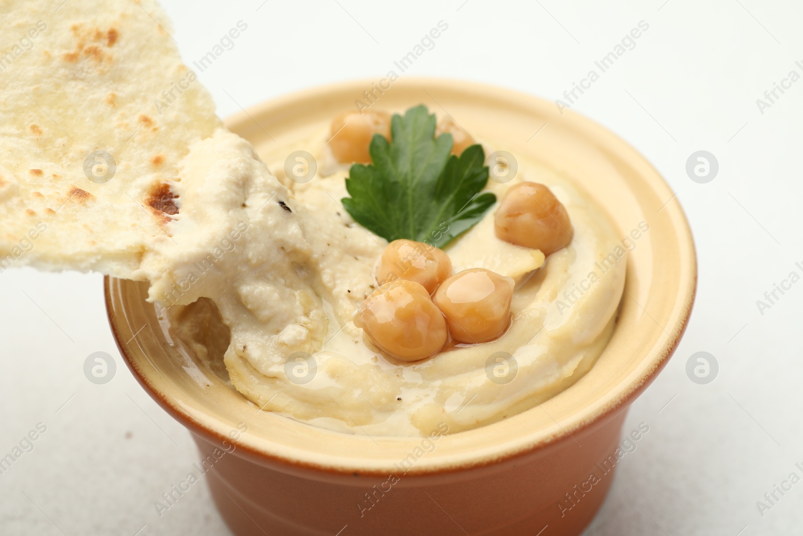 Photo of Delicious hummus with parsley, chickpeas and pita on white table, closeup