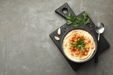 Photo of Delicious hummus with parsley, paprika and chickpeas on grey table, top view. Space for text