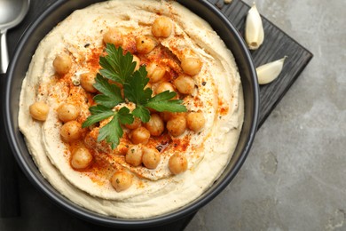 Photo of Delicious hummus with parsley, paprika and chickpeas on grey table, top view