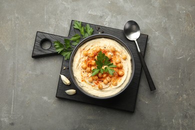 Photo of Delicious hummus with parsley, paprika and chickpeas on grey table, top view