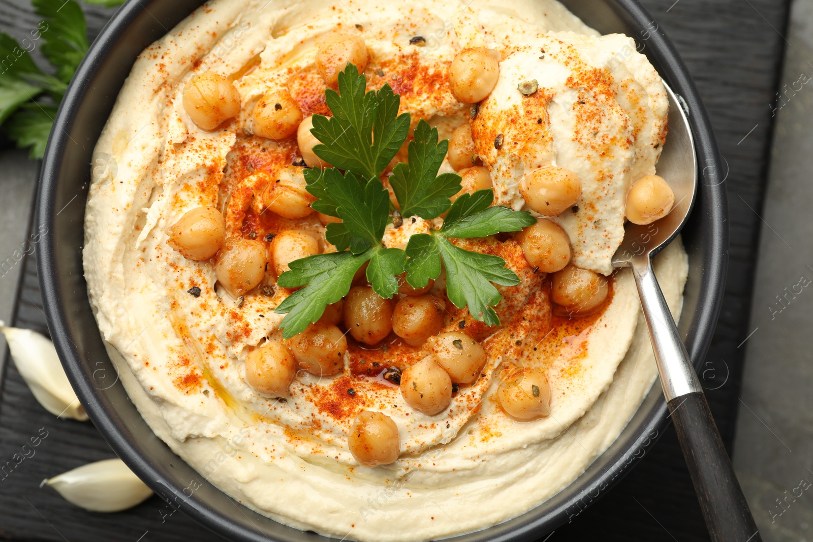 Photo of Delicious hummus with parsley, paprika and chickpeas on table, top view