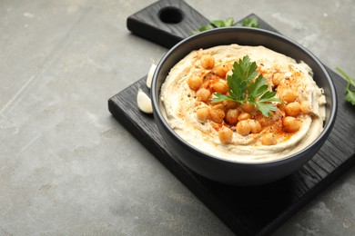 Photo of Delicious hummus with parsley, paprika and chickpeas on grey table, closeup. Space for text