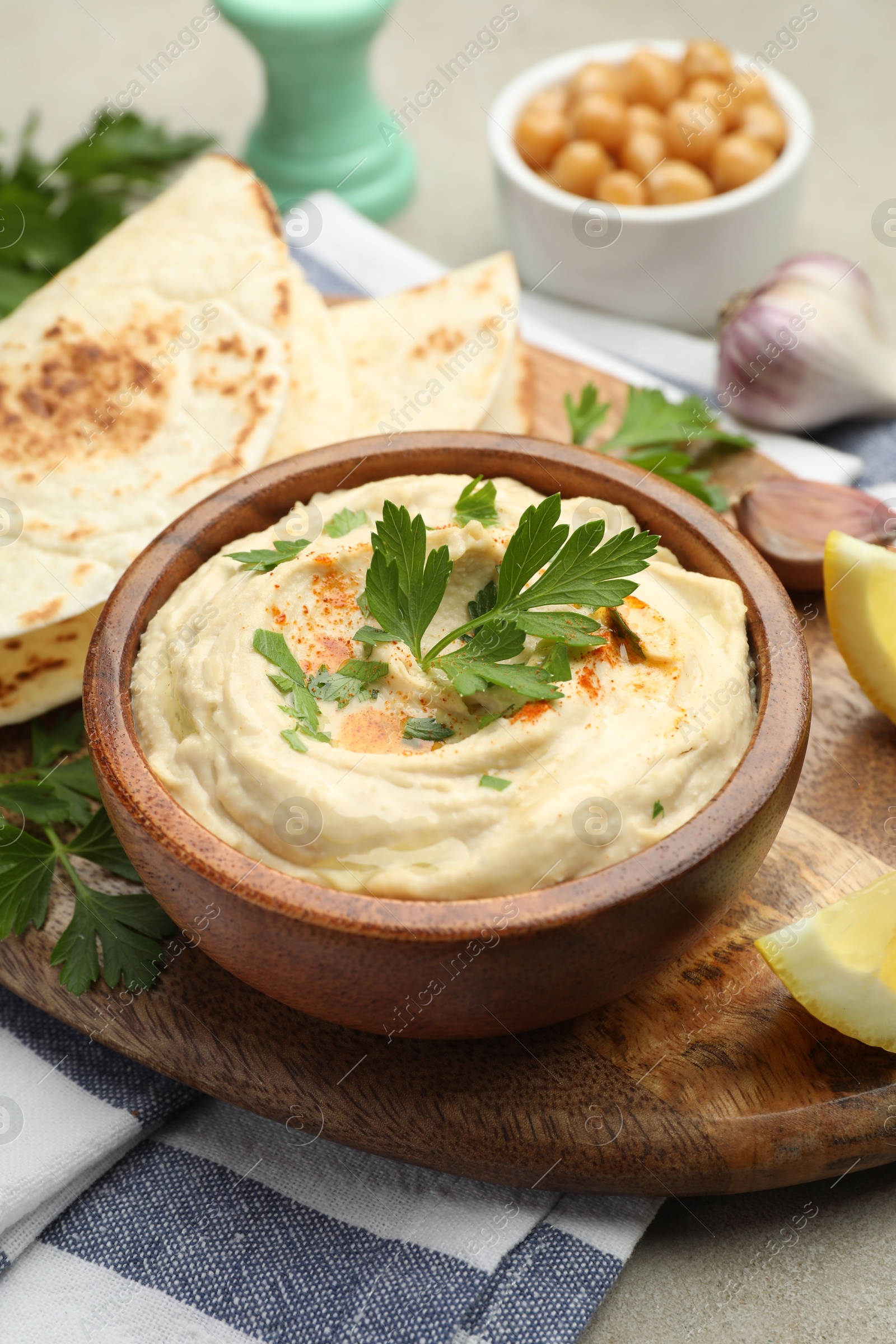 Photo of Delicious hummus with parsley, paprika and pita on table, closeup