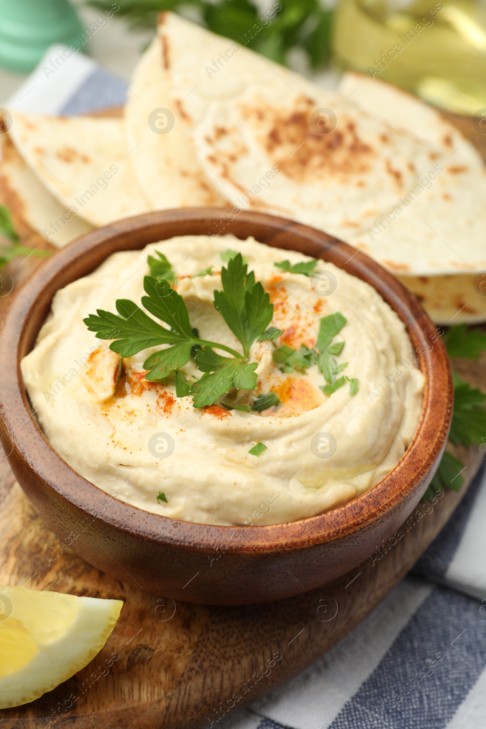 Photo of Delicious hummus with parsley, paprika and pita on table, closeup