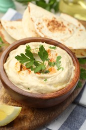 Photo of Delicious hummus with parsley, paprika and pita on table, closeup