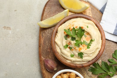 Photo of Delicious hummus with parsley, paprika, garlic and lemon on grey table, top view