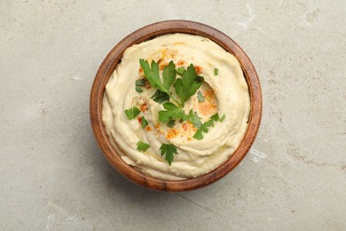 Photo of Delicious hummus with paprika and parsley in bowl on grey background, top view