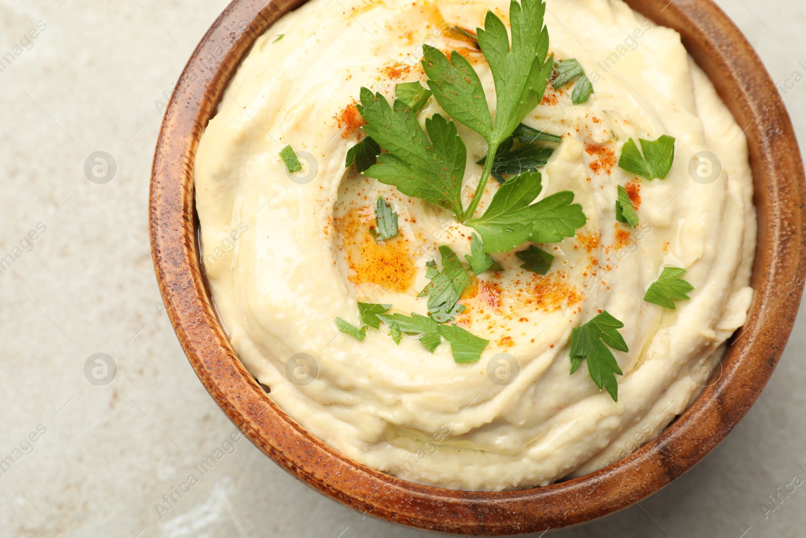 Photo of Delicious hummus with paprika and parsley in bowl on grey background, top view