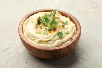 Photo of Delicious hummus with paprika and parsley in bowl on grey background, closeup